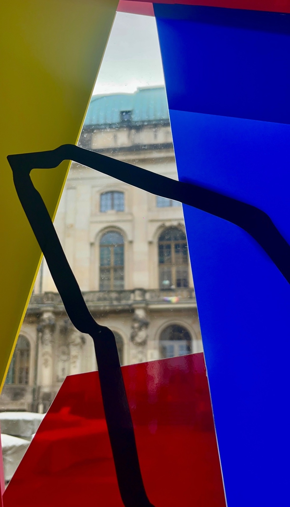 Bunte Klebeband-Komposition auf einem Fenster mit Blick auf historische Architektur
